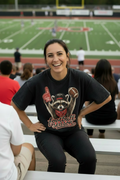 A black acid-wash graphic t-shirt featuring a raccoon holding a foam finger and a football, with 'football season' written in red script below it.